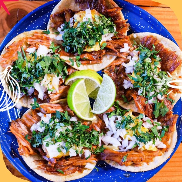 Five Holy Taco al pastor tacos with pineapple, cilantro, onions, and lime on a blue plate.