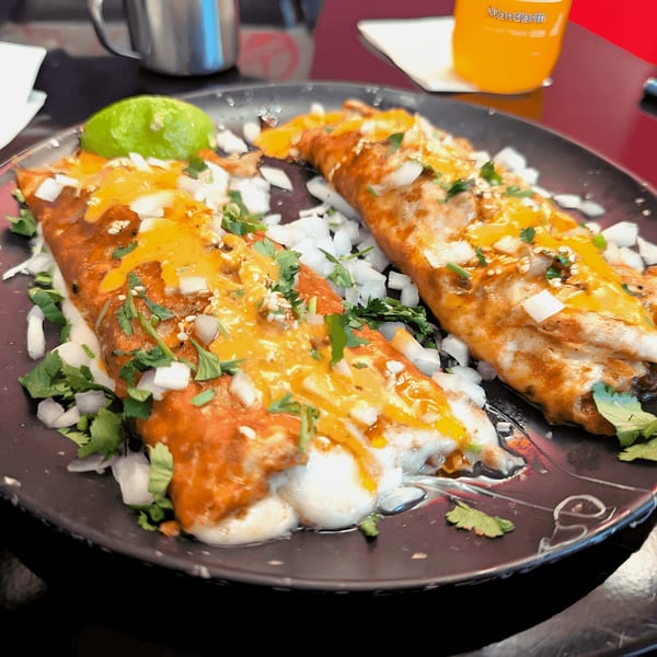 Two Holy Taco quesadillas, topped with melted cheese, onions, cilantro, and a lime wedge.