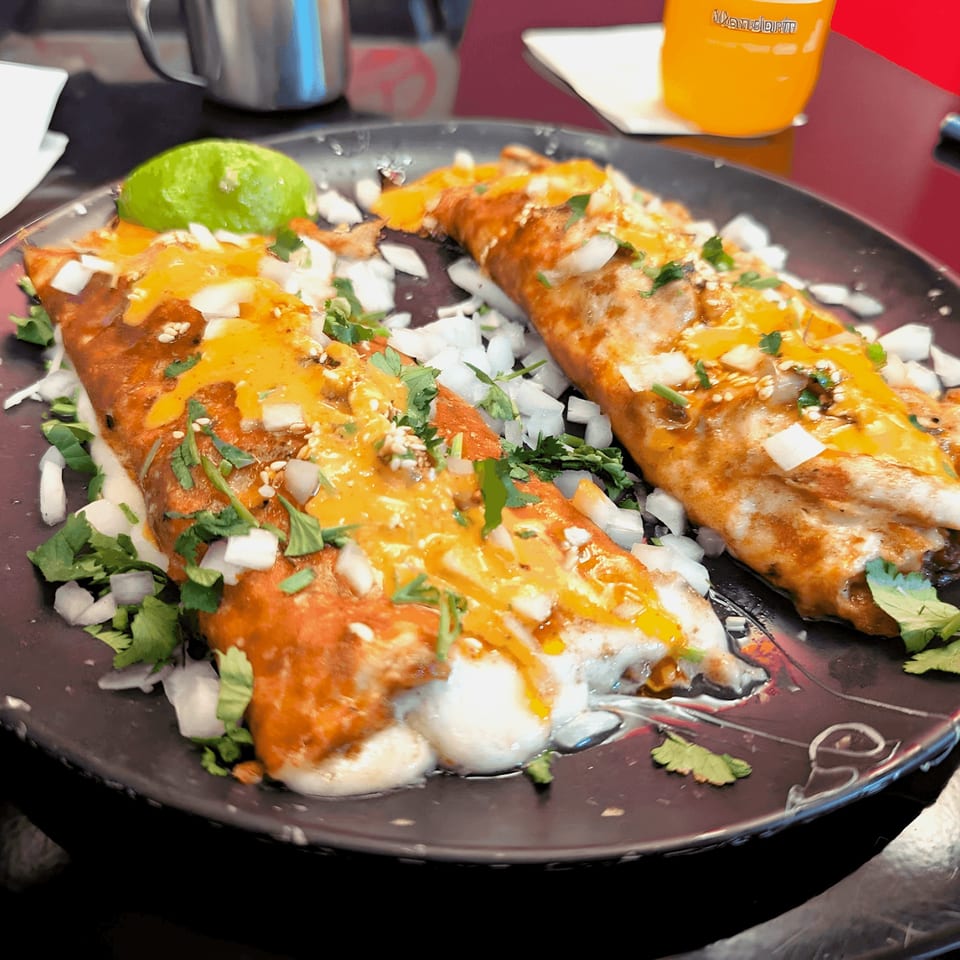 Two Holy Taco quesadillas, topped with melted cheese, diced onions, cilantro, and a lime wedge.